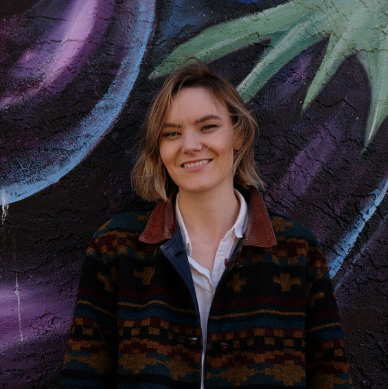 Kaitlyn Threndyle standing in front of a mural, smiling.